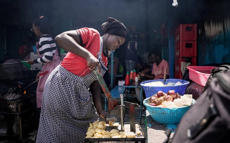 A food vendor uses a manual cutter to slice potatoes for frying at a food stall in Nakuru market, Nakuru, Kenya. (Courtesy: Kreis Visual Storytelling)