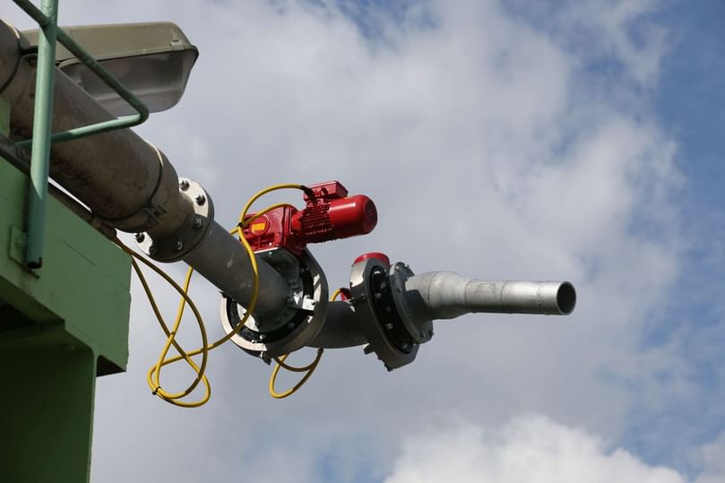 Automated Jet Swivel Device (A-DSV) in operation — a fully automated system for spraying and flushing silos, trucks, and storage areas, featuring dual gear motors for precise 360° rotation and remote-controlled water jet performance.