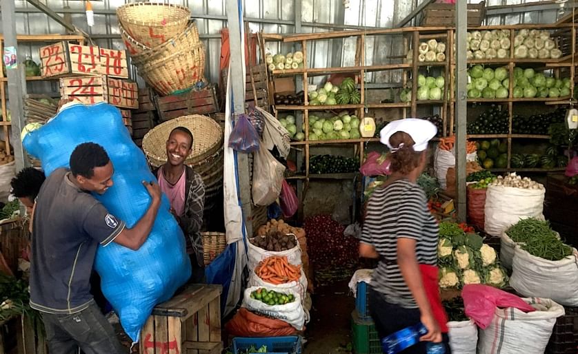 Una mujer con gorro blanco y delantal en el mercado de vegetales de Addis Abeba
