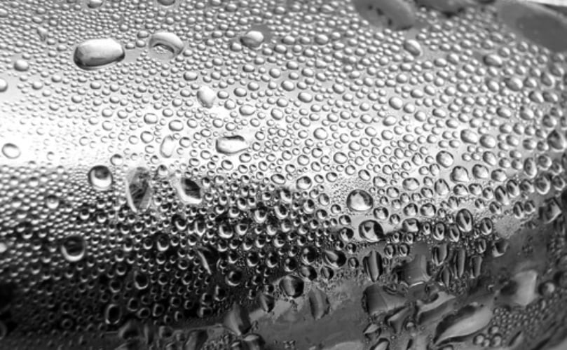 On a copper pipe coated with a hydrophobic material, but without the layer of oil, few droplets form, and they stay on the surface longer and grow much larger before falling away. (Courtesy: Nenad Miljkovic and Rong Xiao / MIT)
On a copper pipe coated with a hydrophobic material, but without the layer of oil, few droplets form, and they stay on the surface longer and grow much larger before falling away. (Courtesy: Nenad Miljkovic and Rong Xiao / MIT)