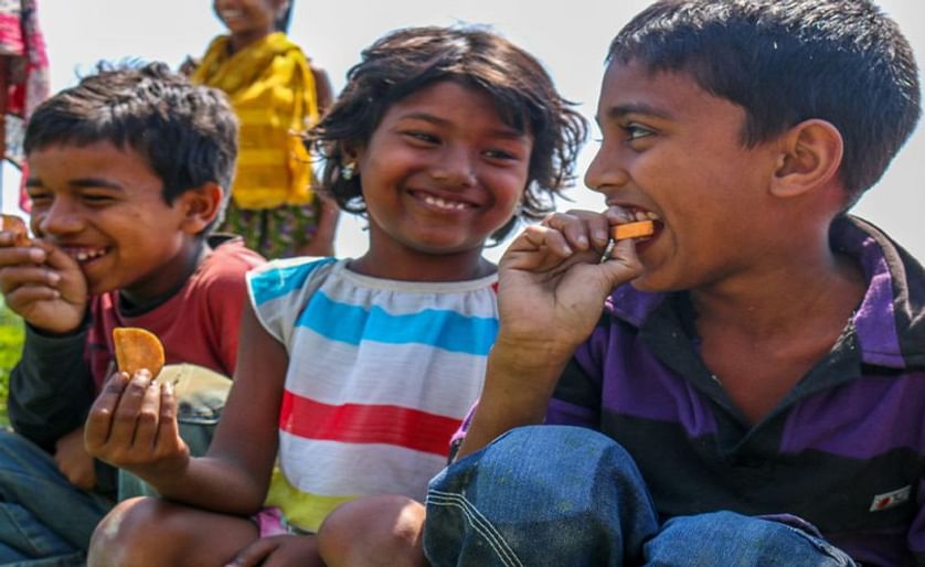 Niños comiendo un camote de pulpa anaranjada recién cosechado en Bangladesh (CIP)