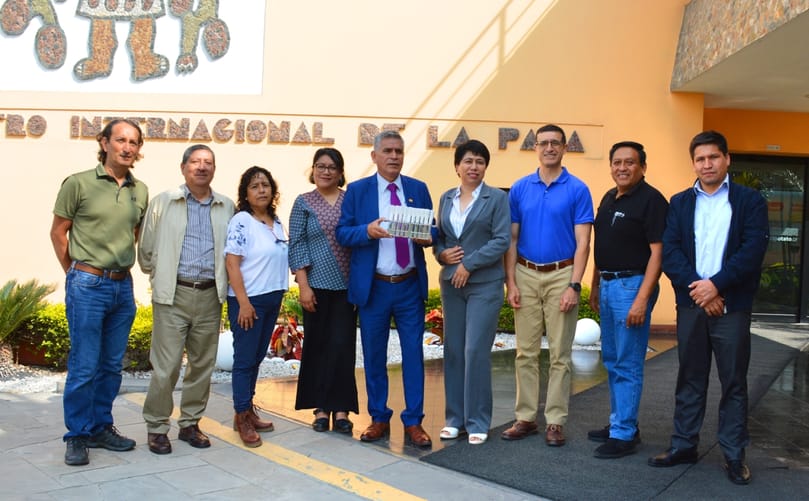 Officials from CIP and INIA exchange biofortified potato plantlets during a ceremony celebrating two decades of research advancing iron-rich potato varieties for improved nutrition.