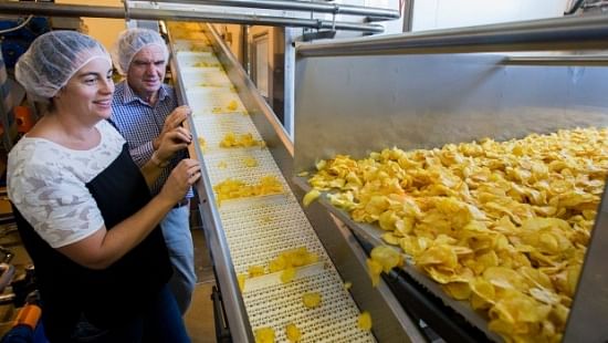 Heartland Potato Chips general manager Charlotte Bowan, and Heartland owner Raymond Bowan watch the cooked chips as they head along the production line. (Courtesy: Fairfax NZ)