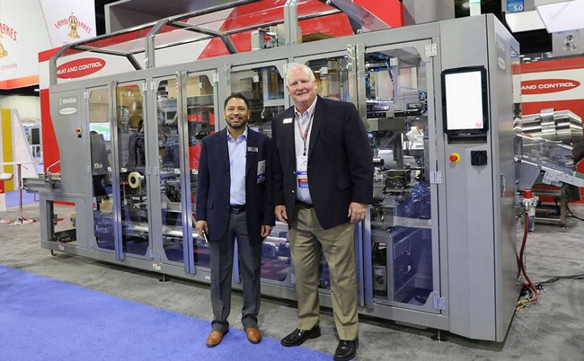 Jorge Carvajal and Jeff Almond next to Ishida’s new snack food case packer, the ACP-700 at SNAXPO 2018