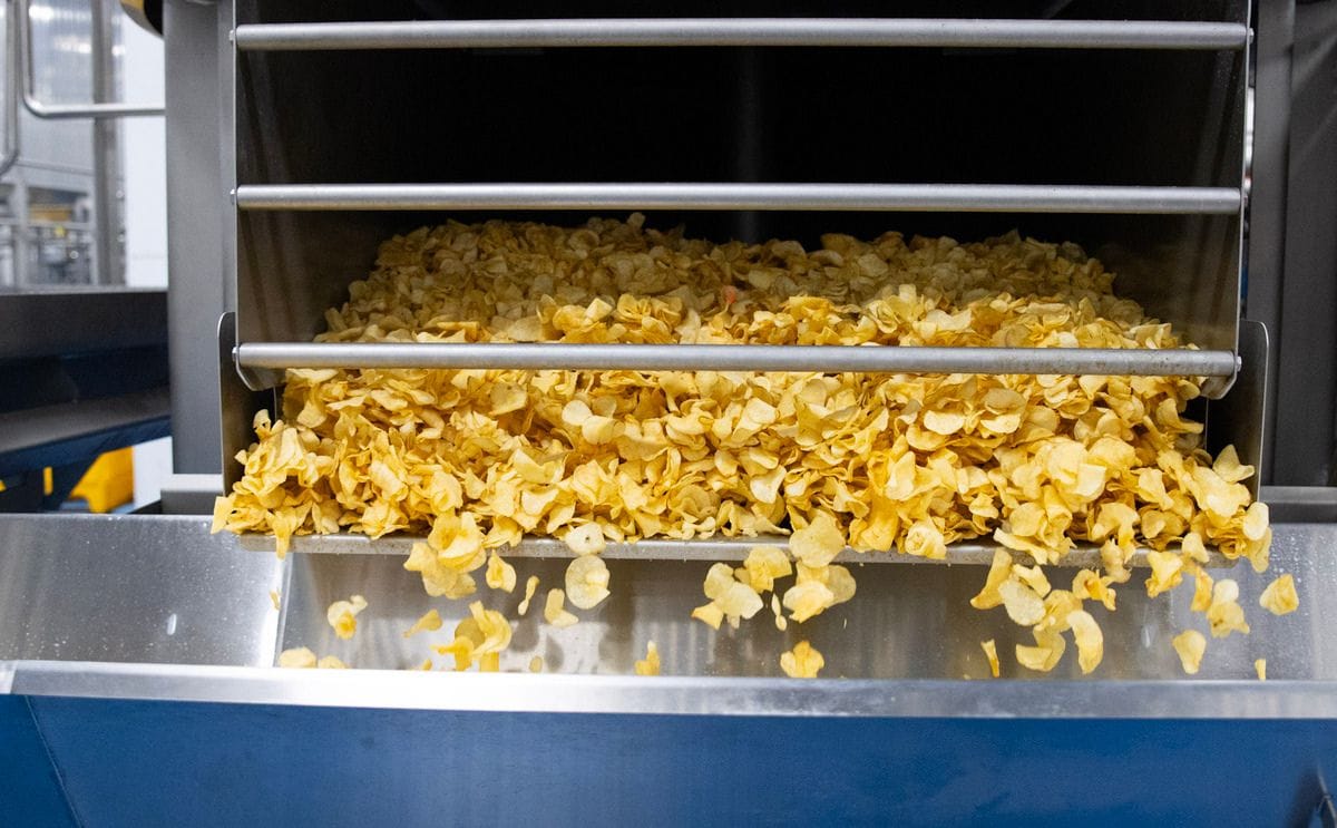 Kettle chips fall out of a centrifuge and onto a conveyor belt in the Taste of Maine Potato Chip Company's factory in Limestone