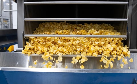 Kettle chips fall out of a centrifuge and onto a conveyor belt in the Taste of Maine Potato Chip Company's factory in Limestone Kettle chips fall out of a centrifuge and onto a conveyor belt in the Taste of Maine Potato Chip Company's factory in Limestone