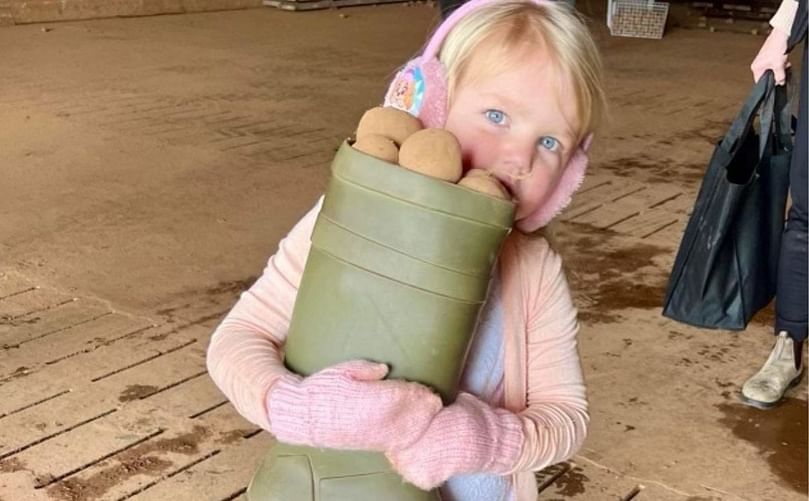 A child is holding a boot filled with potatoes in her hand