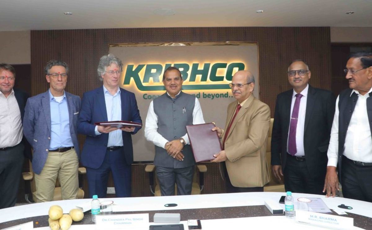 KRIBHCO Managing Director M.R. Sharma and Farm Frites Chairman Pieter de Bruijne exchange signed documents during the official Joint Venture Agreement ceremony, witnessed by KRIBHCO Chairman Dr. Chandra Pal Singh and senior executives.