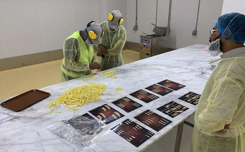 Workers conducting quality checks and sampling freshly cut French fries for consistency. Workers conducting quality checks and sampling freshly cut French fries for consistency.