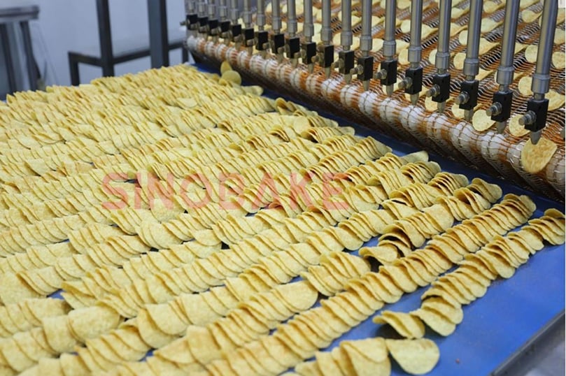 Precise seasoning application on SINOBAKE’s potato chip line, where advanced dispensing technology ensures uniform coating, enhanced flavor, and consistent quality in every batch.