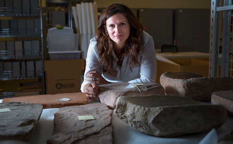 Lisbeth Louderback, assistant professor of anthropology and curator of archaeology at the Natural History Museum of Utah, stands behind large stone metates, the grindstones on which ancient Native Americans processed their food. She discovered microscopic potato granules on 10,900-year-old stone tools in Escalante, Utah.