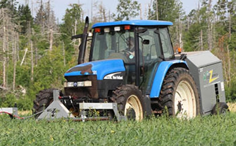 The Weed Zapper at AAFC has a large generator that attaches to a tractor. A wire connects the generator to a large copper pipe at the front of the tractor to zap weeds that it encounters. The Weed Zapper at AAFC has a large generator that attaches to a tractor. A wire connects the generator to a large copper pipe at the front of the tractor to zap weeds that it encounters.