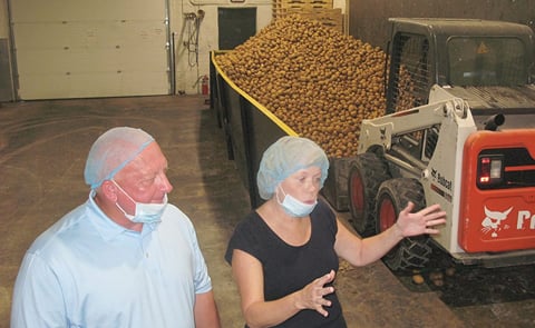 From left, Mister Bee sales director Rob Graham and owner Mary Anne Ketelsen describe how chips are made at the potato hopper at Mister Bee during a press event (Courtesy: Jess Mancini). From left, Mister Bee sales director Rob Graham and owner Mary Anne Ketelsen describe how chips are made at the potato hopper at Mister Bee during a press event (Courtesy: Jess Mancini).
